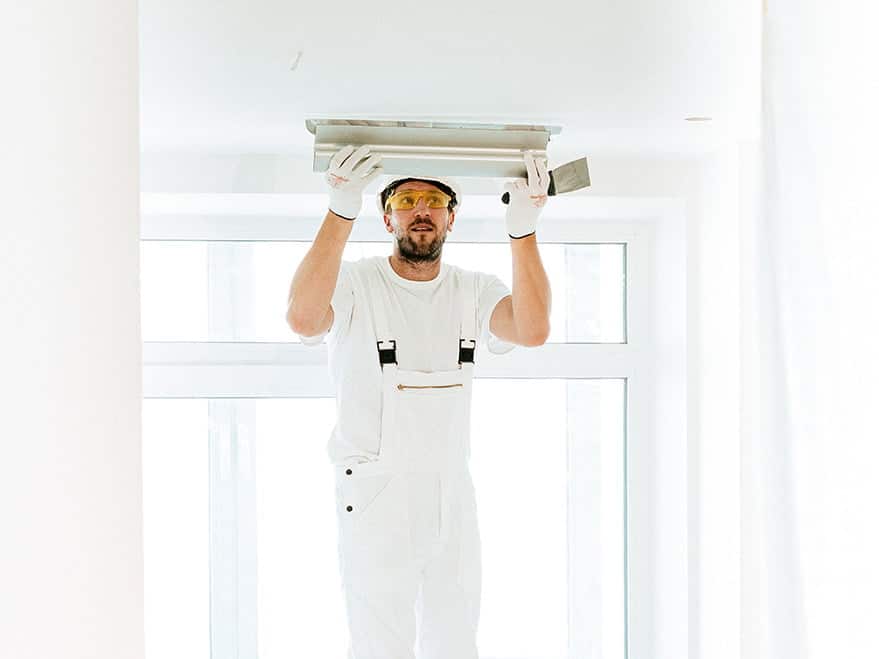 un plaquiste qui pose du plâtre sur le plafond