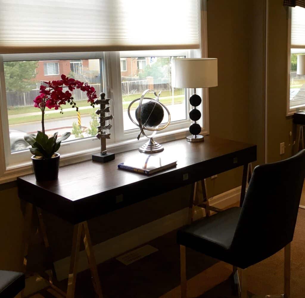 Clean desk in front of a window shaded by roll shades