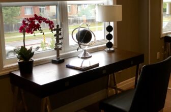 Clean desk in front of a window shaded by roll shades